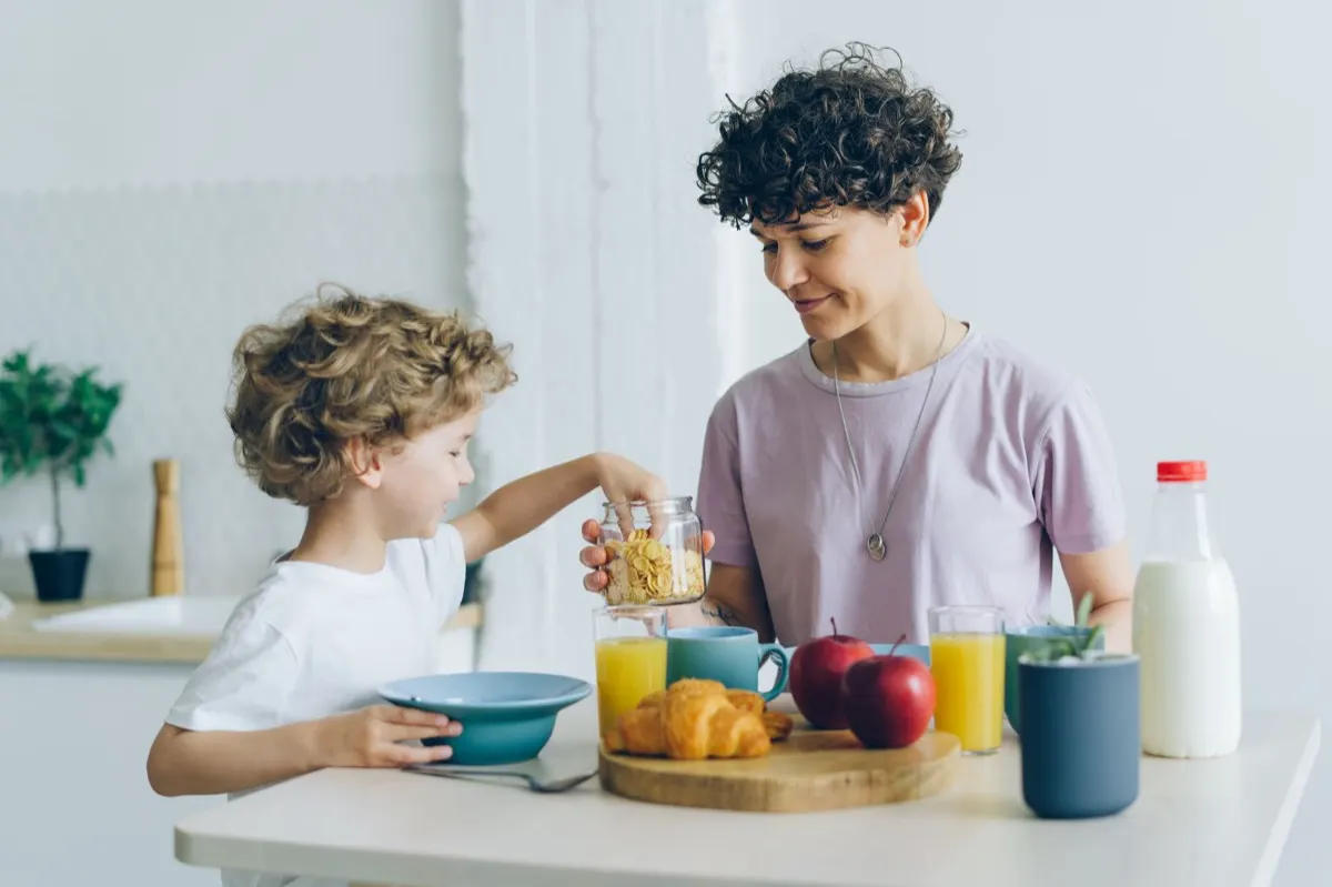 A parent helping a child at the kitchen table at home