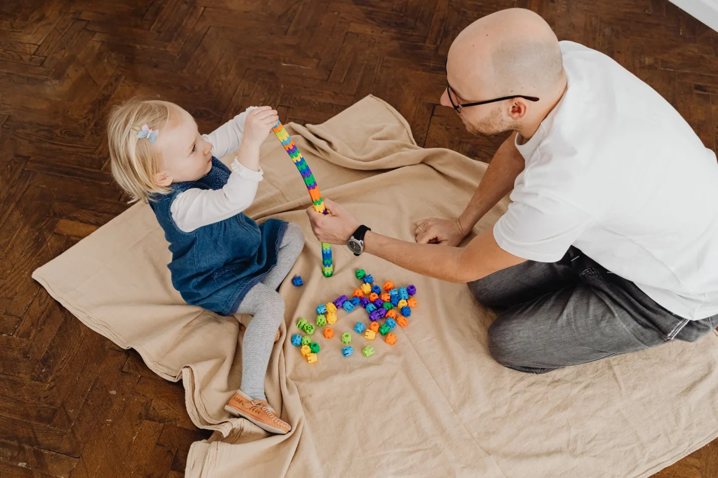 A toddler playing with wooden blocks on the floor