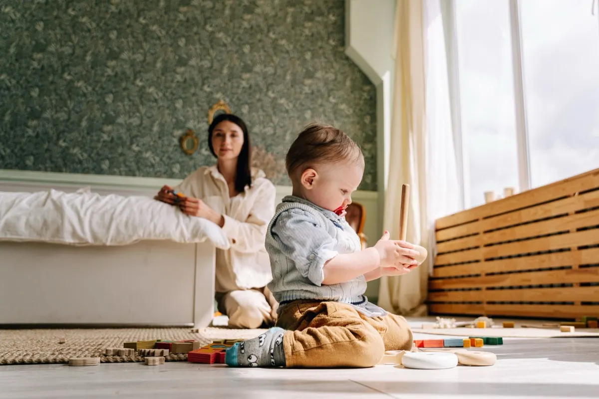 A parent and young child playing together on the floor at home